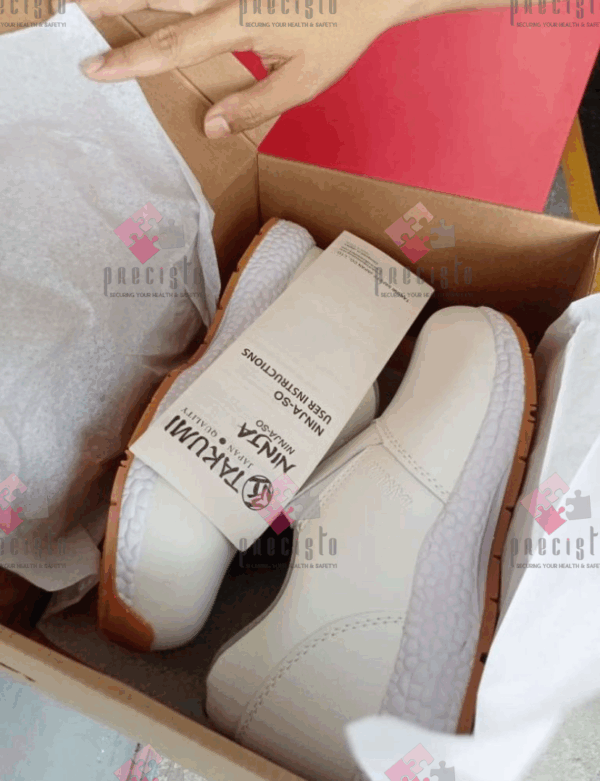 A person holding a box containing a pair of white shoes.